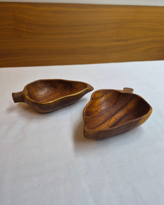 Two wooden bowls on a white surface with a wooden background