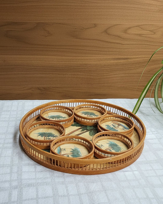 Wicker tray with decorative items on a checkered tablecloth, plant in the background