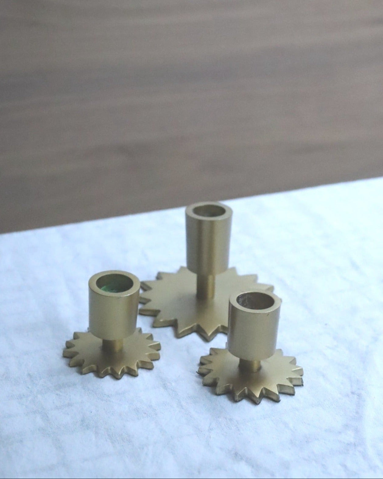 Set of brass gears on a white surface with a wooden background