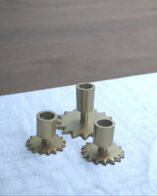 Set of brass gears on a white surface with a wooden background