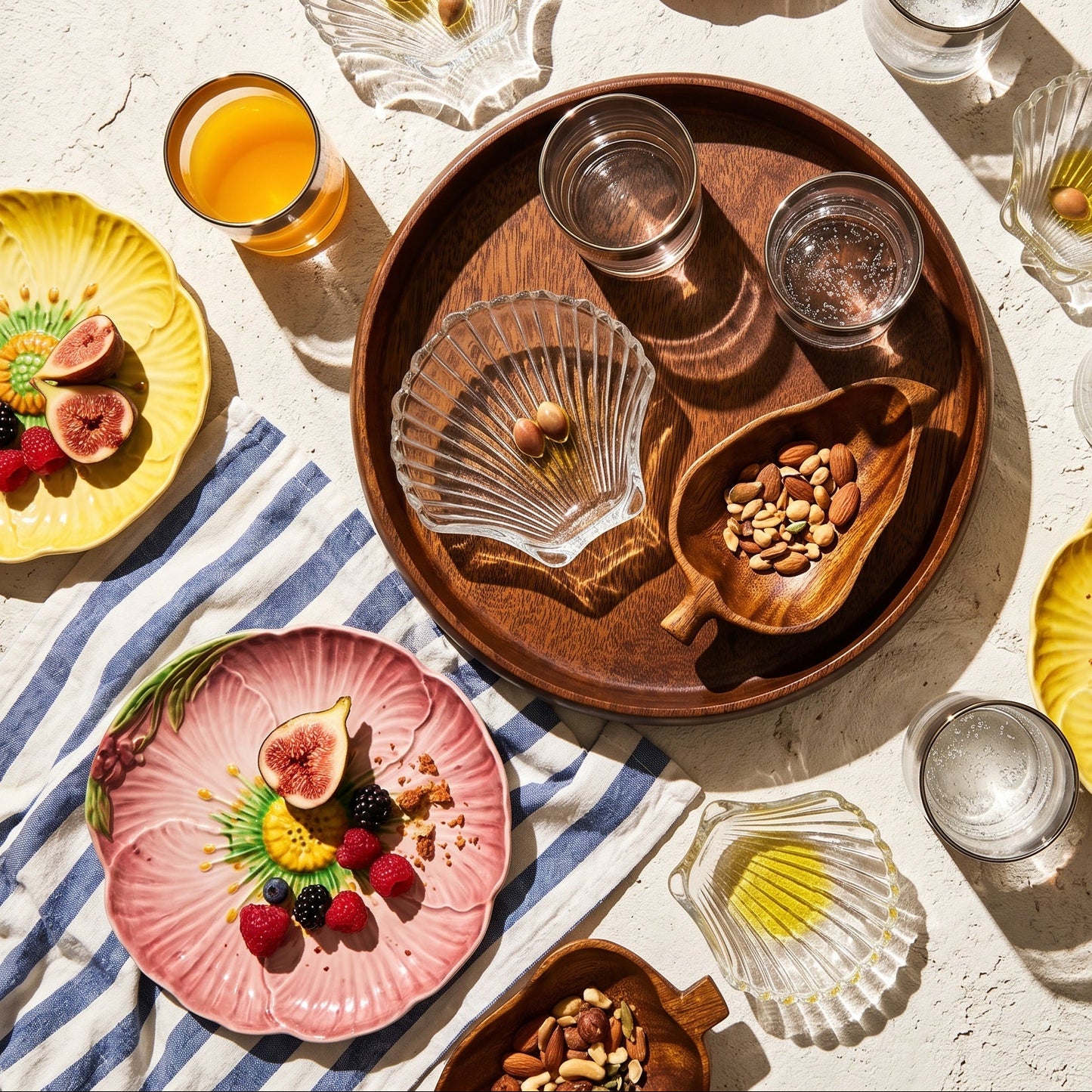 Table setting with plates, glasses, and a wooden tray on a light surface.