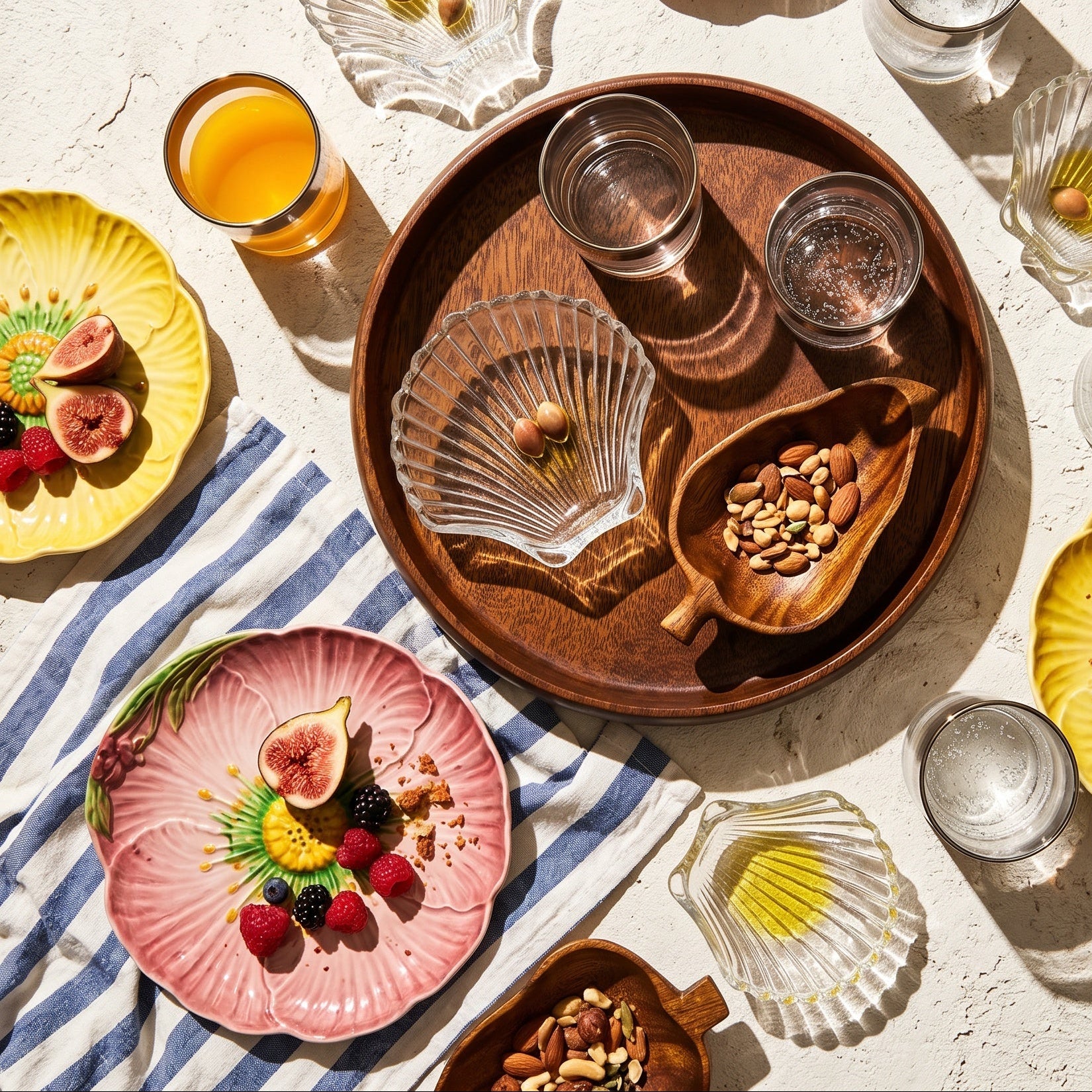Table setting with plates, glasses, and a wooden tray on a light surface.