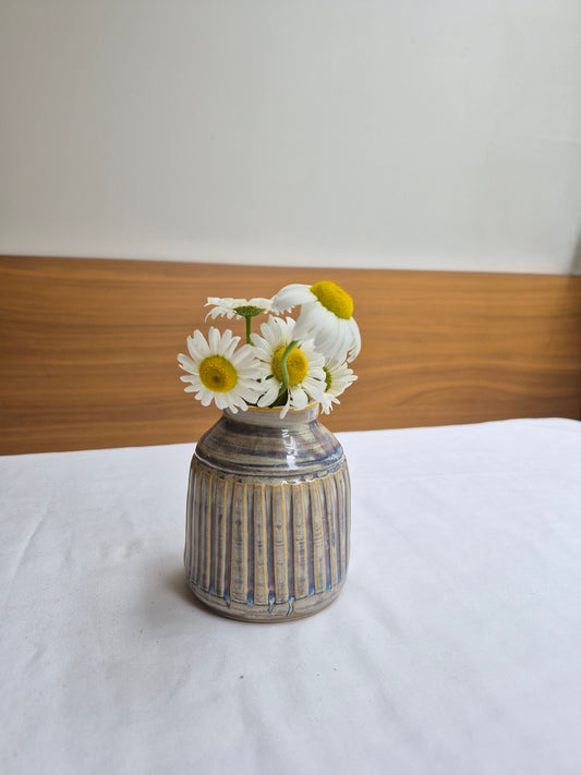 Small ceramic bottle with flowers on a wooden surface